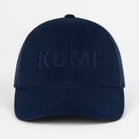 Gorra KUMI en color azul marino vista de frente, con bordado monocromático de “KUMI” sobre pana de algodón orgánico
