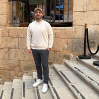 Modelo masculino luciendo la KUMI Natural Unisex Crewneck, corte regular, de pie en escaleras históricas