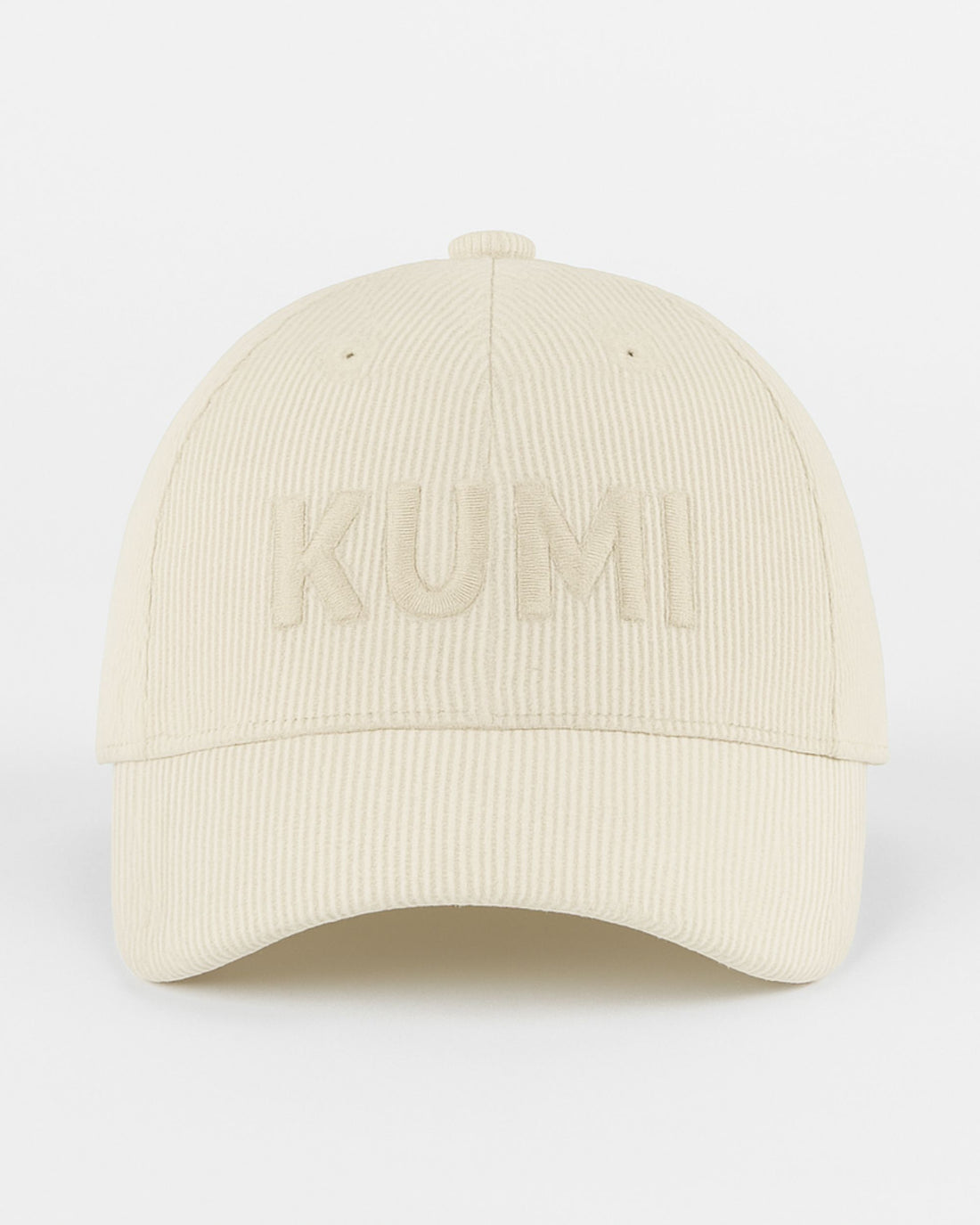Gorra KUMI en color natural vista de frente, con bordado tono sobre tono de la palabra “KUMI” en pana de algodón orgánico