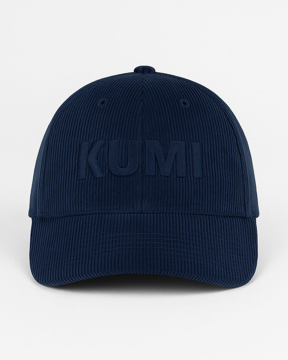 Gorra KUMI en color azul marino vista de frente, con bordado monocromático de “KUMI” sobre pana de algodón orgánico