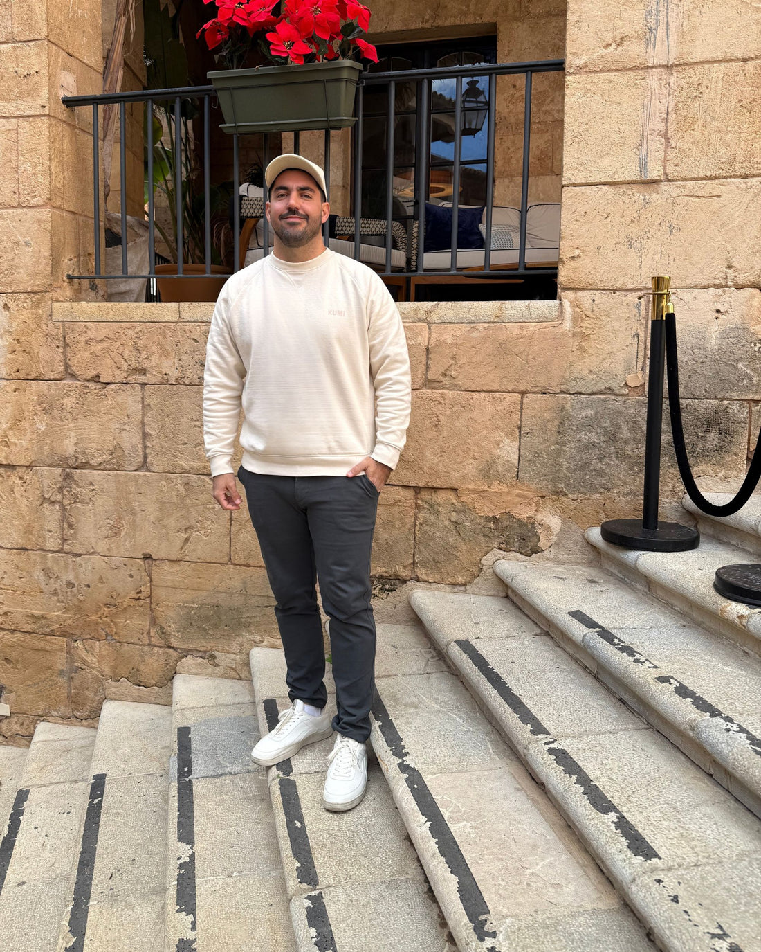 Modelo masculino luciendo la KUMI Natural Unisex Crewneck, corte regular, de pie en escaleras históricas