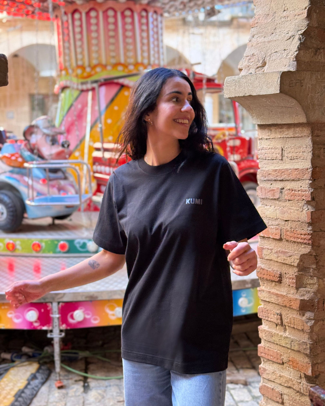 Modelo con Camiseta KUMI negra de algodón orgánico, corte regular, en ambiente urbano